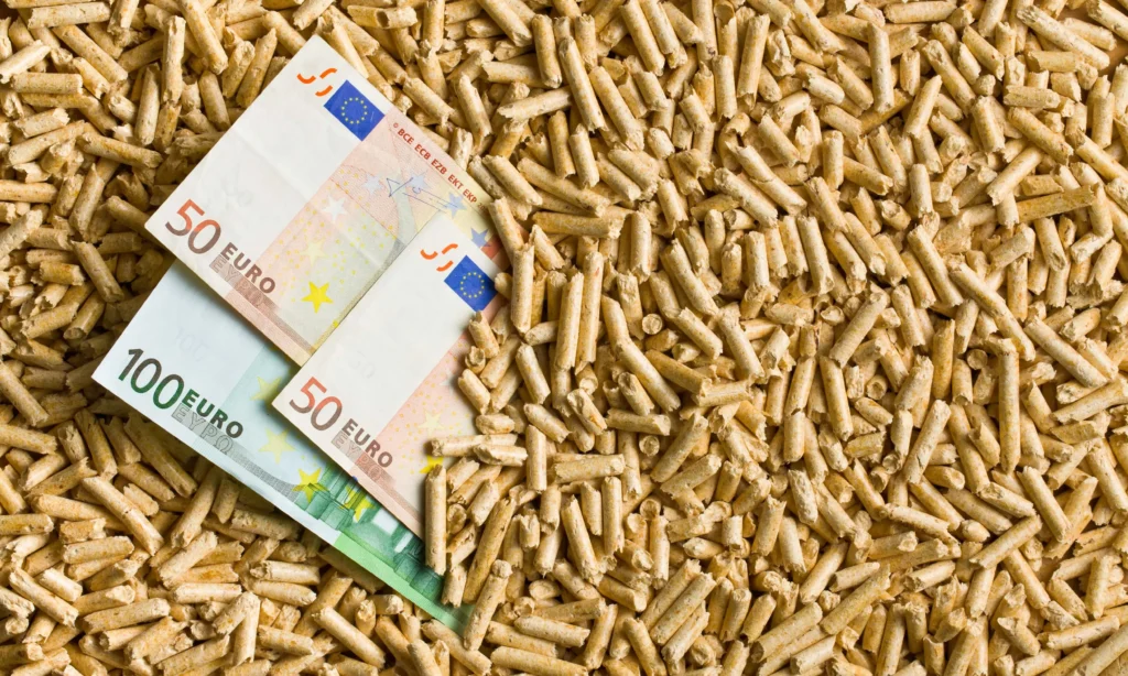Banknoty euro na tle pelletu drzewnego, symbolizujące koszty związane z ceną pelletu za tonę w Europie.