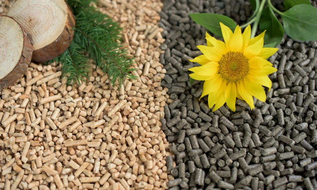 Pellet drzewny i słonecznikowy na tle drewna i słonecznika, pokazujące różnice w rodzajach pelletu i ich cenach za tonę.