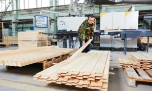 Pracownik obsługujący maszynę do produkcji palet drewnianych. Nowoczesne technologie w procesie cięcia i obróbki drewna.